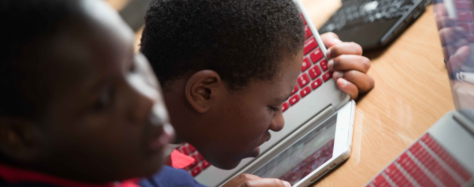 A photo of a student using a Chromebook laptop closely held to his face